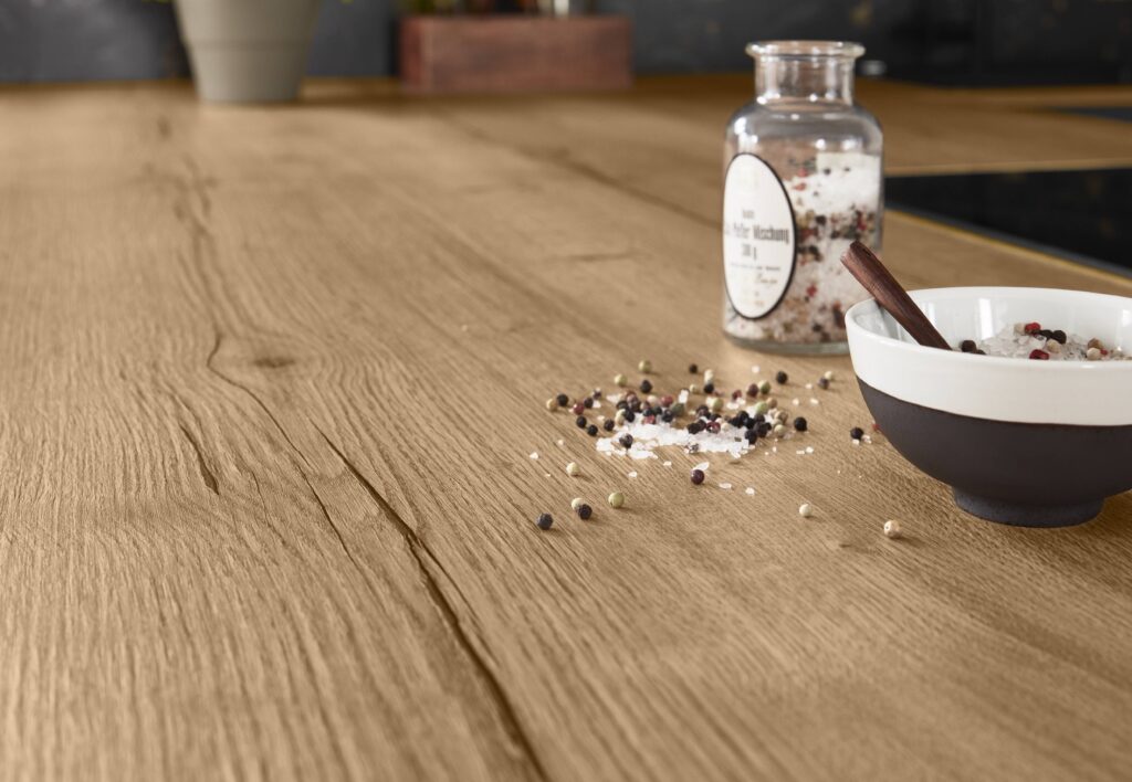 Bocal de sel et poivre sur un plan de travail en bois clair, à côté d'un bol avec une cuillère en bois.