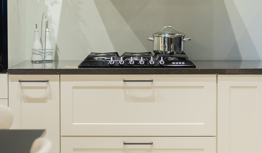 Gros plan sur un meuble d'une cuisine cottage aux façades blanches, avec une taque de cuisson au gaz SMEG
