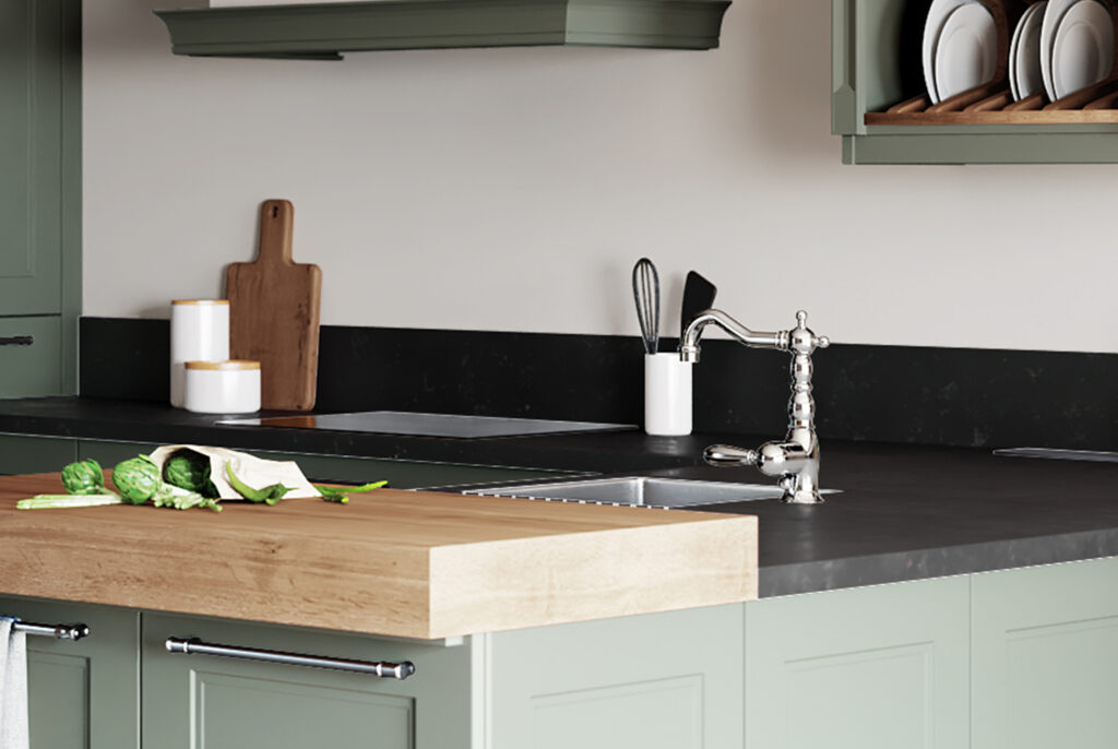 Plan de travail de cuisine en pierre naturelle noire avec évier en acier, planche à découper en bois et choux de Bruxelles sur une surface en bois.