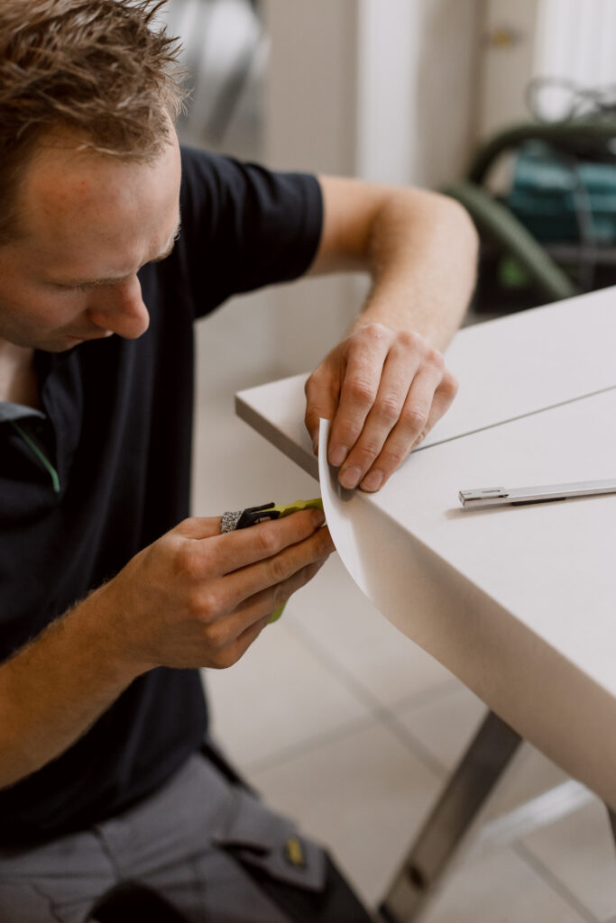 Homme qui recouvre une façade de cuisine avec un vinyle