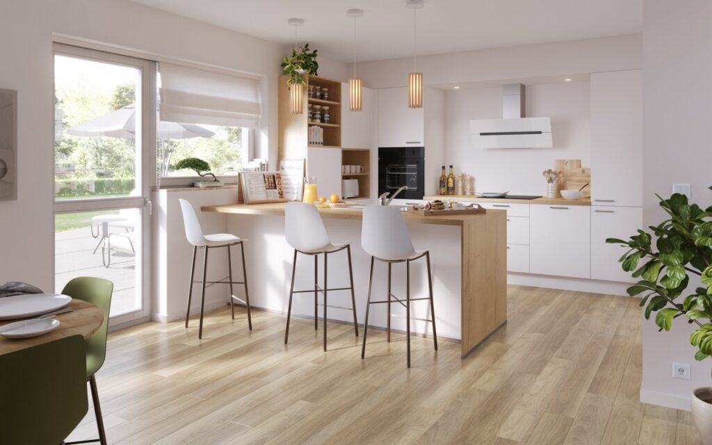 Cuisine ouverte blanche et bois clair avec îlot central, trois tabourets blancs, four encastré, hotte murale, suspensions et grande porte-fenêtre.