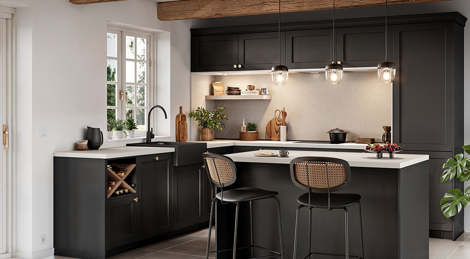 Cuisine en U avec meubles noirs, plan de travail blanc et îlot central avec deux tabourets noirs. Une fenêtre, trois suspensions en verre et des accessoires en bois sont visibles.