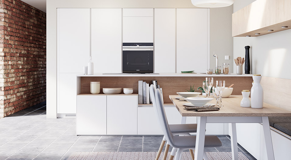 Cuisine moderne blanche avec armoires hautes, four encastré noir au centre, plan de travail en bois clair et table dressée avec chaises grises au premier plan.