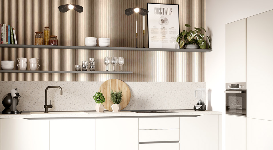 Cuisine blanche avec meubles bas et colonnes, plan de travail clair, évier noir, plaques de cuisson, blender, machine à café et étagères murales avec vaisselle, bocaux et plante.