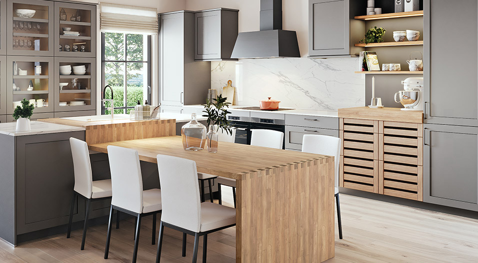 Cuisine moderne avec armoires grises, plan de travail et table en bois clair, quatre chaises blanches, hotte noire, étagères ouvertes et évier devant une fenêtre.