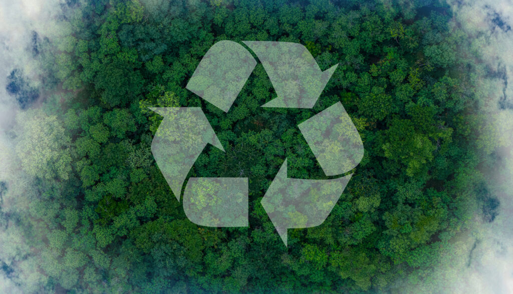 Vue aérienne d’une forêt dense aux feuillages verts, avec un grand symbole de recyclage translucide centré sur l’image et de la brume sur les bords.