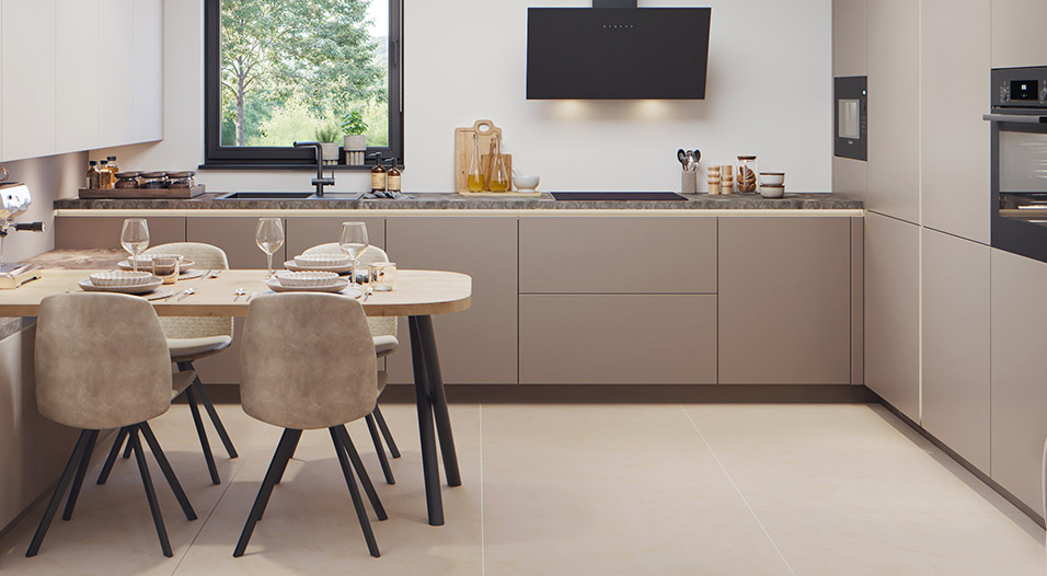 Cuisine moderne avec meubles beiges sans poignées, plan de travail gris, table ronde en bois clair avec quatre chaises taupe, hotte noire et fenêtre au-dessus de l’évier.