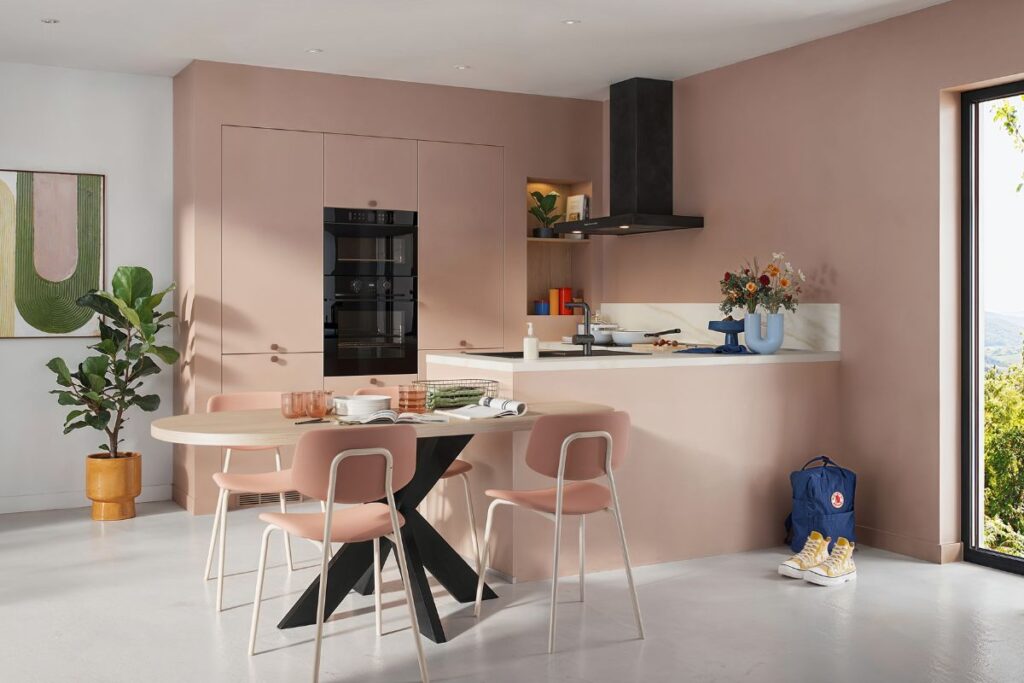 Cuisine rose pale avec une table ronde et une hotte noire
